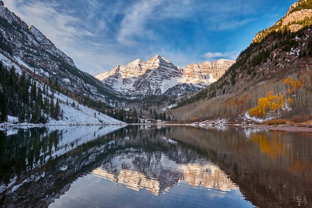 Maroon Bells and Maroon Lake with reflection of rocks and mountains in snow around at autumn in Colorado Rocky Mountains, USA.
