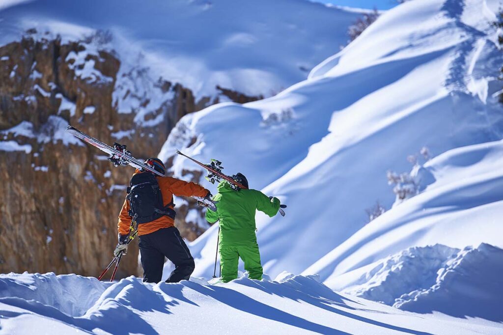 Two male skiers trudging up deep snow covered mountain, Aspen, Colorado, USA